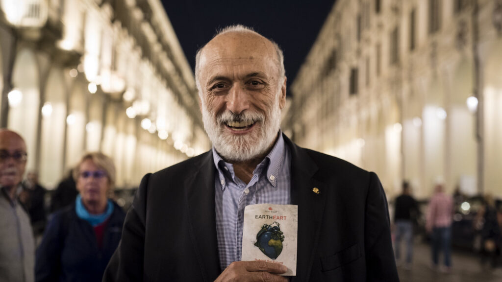 Carlo Petrini durante il Salone del gusto, Torino, 2016. con un libro dedicato alle tematiche ambientali sul cuore